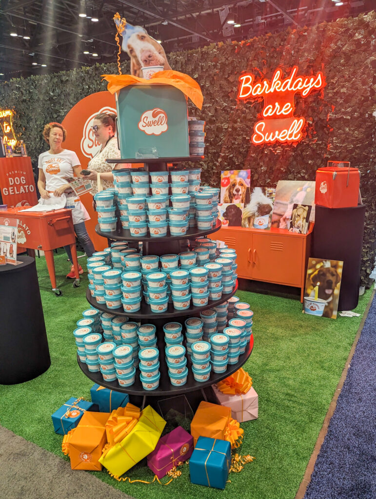 Stack of geleto containers that looks like a Christmas tree with neon sign in that back that says "Barkdays are Swell"