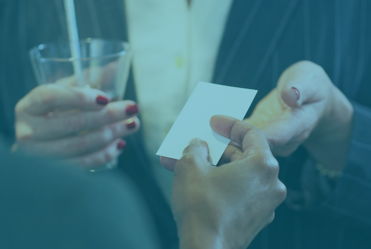 Two women exchanging a business card with heading How to Successfully Network at an In-person Event