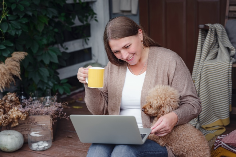 woman holding a mug of coffee and using a laptop with a dog beside her | Demystifying Google E-E-A-T for SEO: Your Guide to Expertise, Experience, Authoritativeness, and Trustworthiness