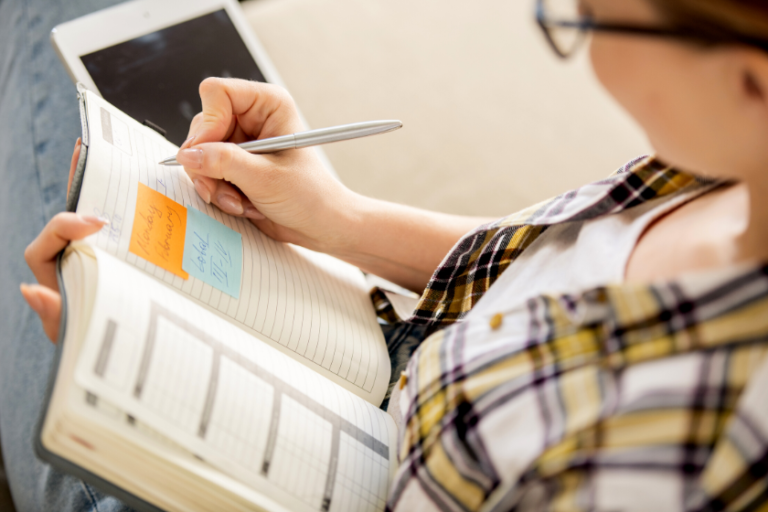 woman writing in a planner | How to Do a Mid-Year Check-in for Your Business Goals
